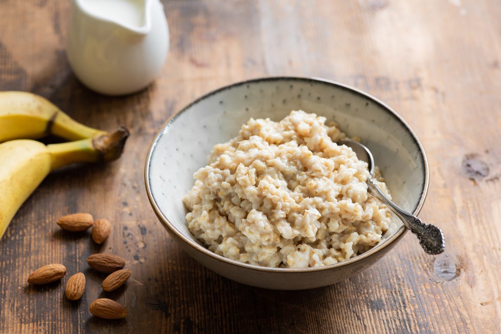 oatmeal porridge in bowl served with banana, almonds and almond milk for healthy breakfast old wooden table background healthy lifestyle concept