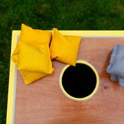 above view of a cornhole game with yellow and gray beanbags