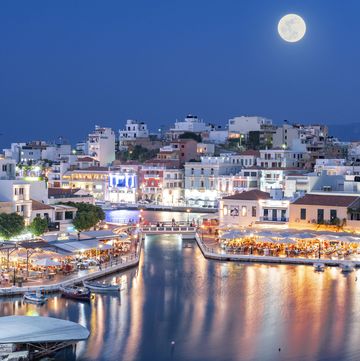 harbor and lake of agios nikolaos town lit by the full moon during blue hour, lasithi prefecture, crete island, greece