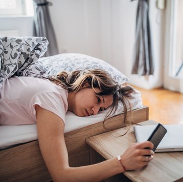 young woman is waking up and looking at her smart phone