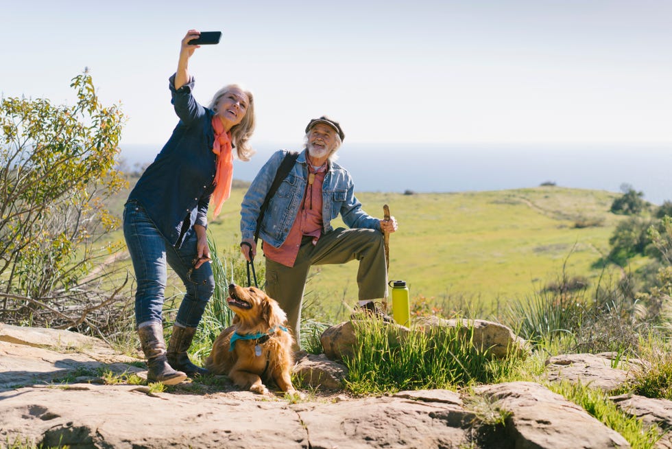senior couple taking selfie with dog during hike on sunny day