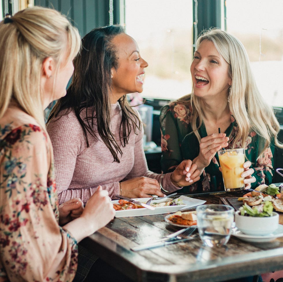 a front view shot of three mid adult women enjoying brunch together in a restaurant