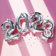 silver numbers 2023 new year balloons among confetti in sunlight on pink background