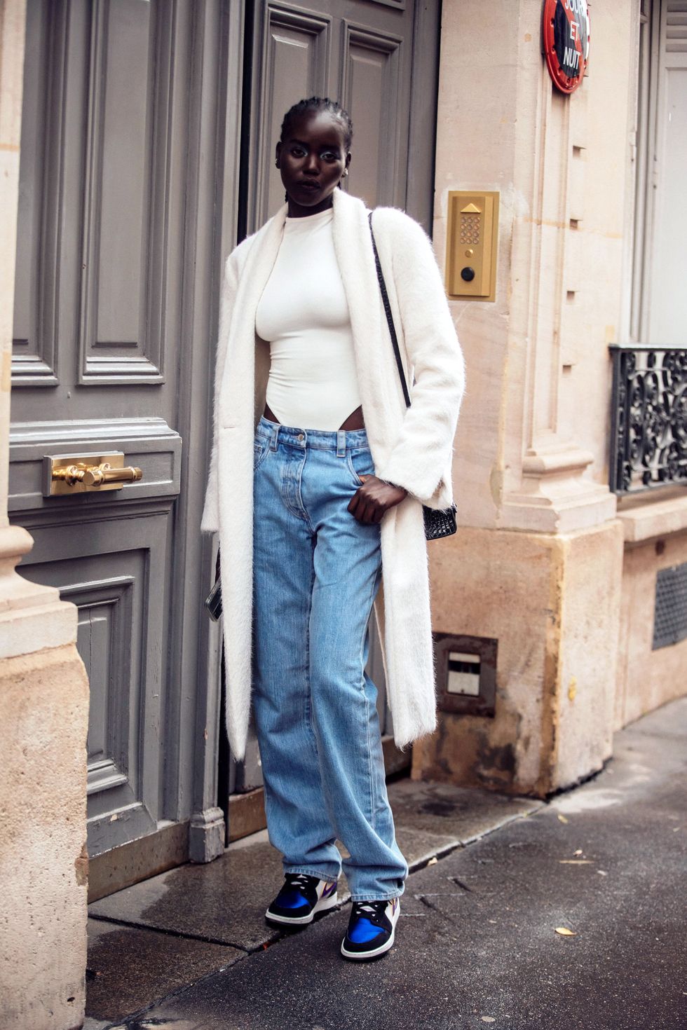 paris, france   october 03 model adut akech wears a log white fuzzy jacket, white body suit, blue jeans, and white and blue nike sneakers after the lanvin show on october 03, 2021 in paris, france photo by melodie jenggetty images