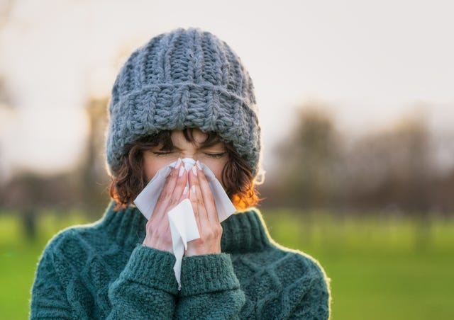 close up of a woman suffering from the symptoms of a cold outdoors during winter