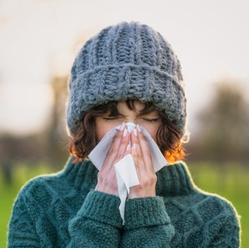 close up of a woman suffering zapatillas the symptoms of a cold outdoors during winter