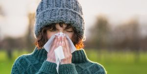 close up of a woman suffering from the symptoms of a cold outdoors during winter