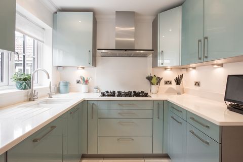 a general interior view of a modern metallic green fitted kitchen with white quartz worktop with undermount sink within a home