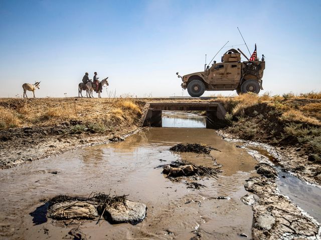 topshot   youths ride donkeys near a us military vehicle crossing a stream polluted by an oil spill near the village of sukayriyah, in the countryside south of rumaylan rmeilan in syrias kurdish controlled northeastern hasakeh province, on july 19, 2020   oil pollution in syria has become a growing concern since the 2011 onset of a civil war that has taken a toll on oil infrastructure and seen rival powers compete over control of key hydrocarbon fields in the kurdish held northeast, a large storage facility in the rmeilan oil field in hasakeh province is of particular concern, with leaks from the gir zero storage facility have been suspected since at least 2014, and the latest just in march 2020 photo by delil souleiman  afp photo by delil souleimanafp via getty images
