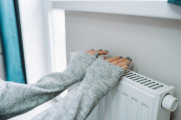 two female hands in warm sweater trying to keep warm near battery radiator central heating problems, cold temperature