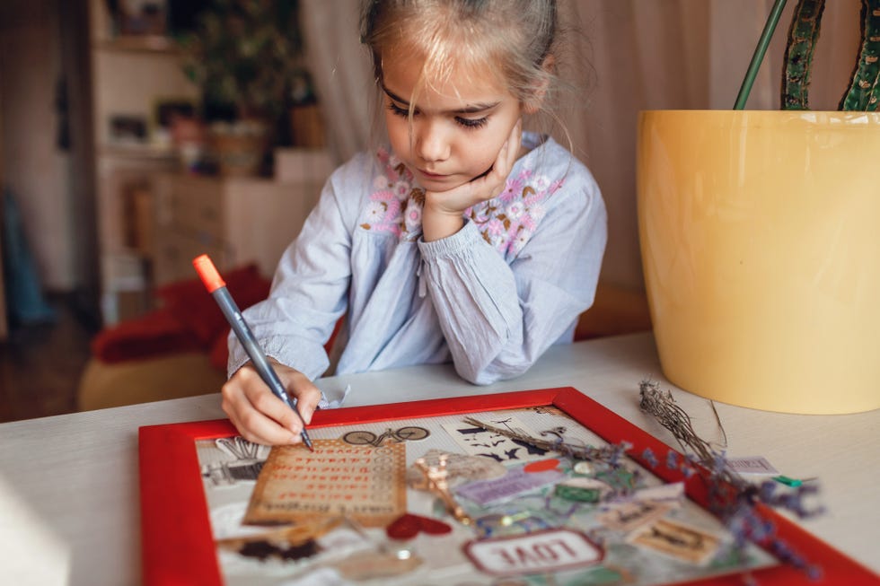 cute girl dreaming about travel to france and creating mood board with sheets of paper, pictures and words