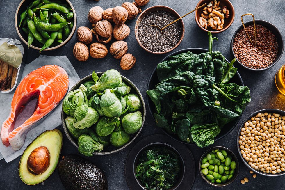 top view of food rich in omega 3 fatty acids on the table salmon steak, avocado, brussels sprout, wakame, soybeans, lentil seeds, chia seeds, flax seeds, walnuts and avocado are on the table