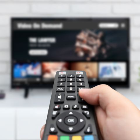 man watching tv, remote control in hand vod service on tv