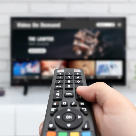 Homme regardant la télévision, télécommande à la main homme regardant la télévision, télécommande à la main service vod à la télévision