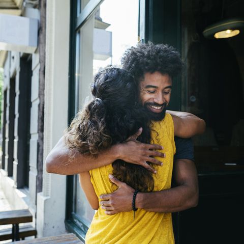 two friends greeting each other and embracing outside a restaurant