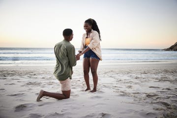 engagement captions boyfriend kneeling on one knee on a beach proposing to his smiling girlfriend