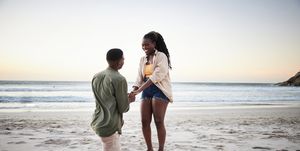 engagement captions boyfriend kneeling on one knee on a beach proposing to his smiling girlfriend