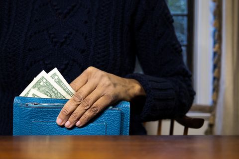 woman holding wallet with us $1 paper bills showing