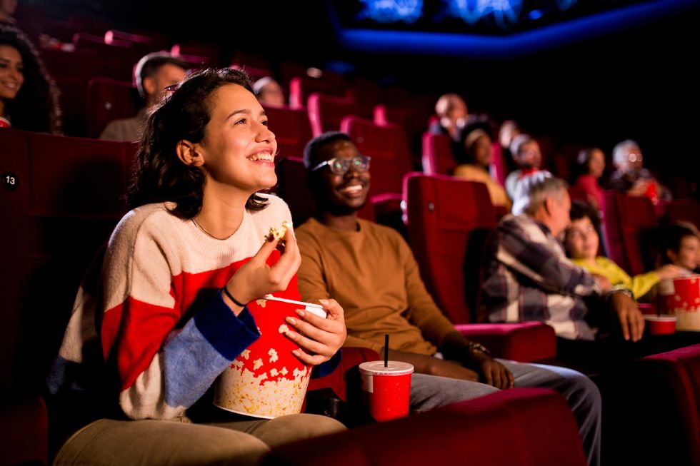 girl watching a comedy movie at the cinema with her african american friend