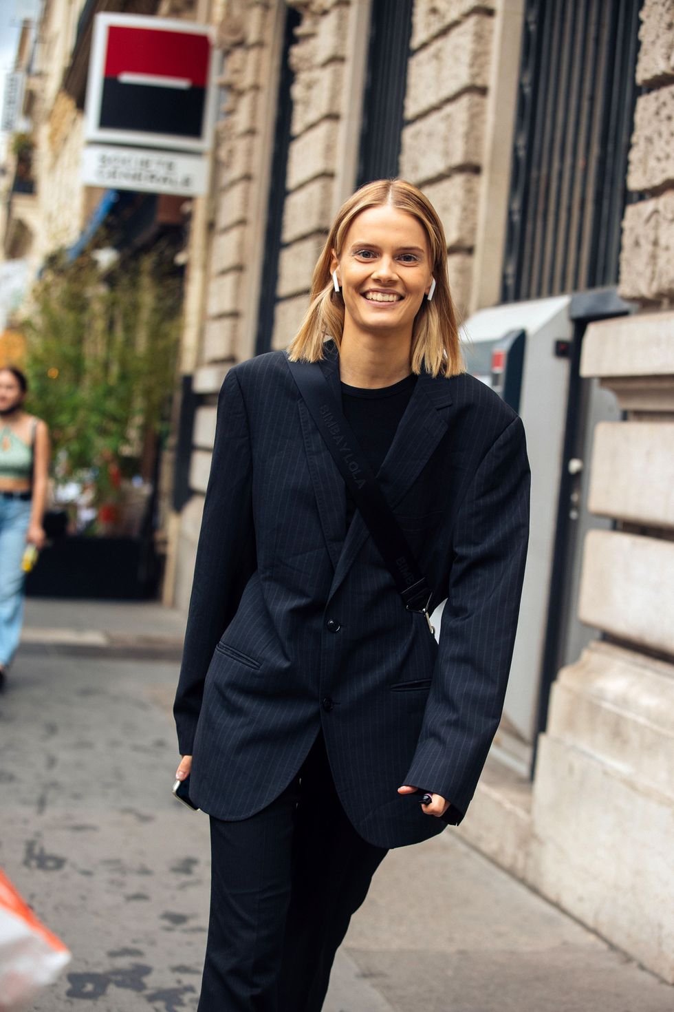 paris, france july 07 model daria koshkina wears apple airpods, a boxy dark blue pinstripe blazer, black pants, and a bimba y lola bag at the fendi show at palais brongniart during couture fashion week fallwinter 2022 on july 07, 2022 in paris, france photo by melodie jenggetty images