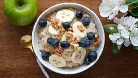 bowl of oatmeal porridge with banana, blueberry, walnuts on a wooden table top view