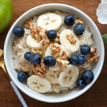 bowl of oatmeal porridge with banana, blueberry, walnuts on a wooden table top view