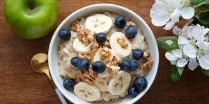 bowl of oatmeal porridge with banana, blueberry, walnuts on a wooden table top view