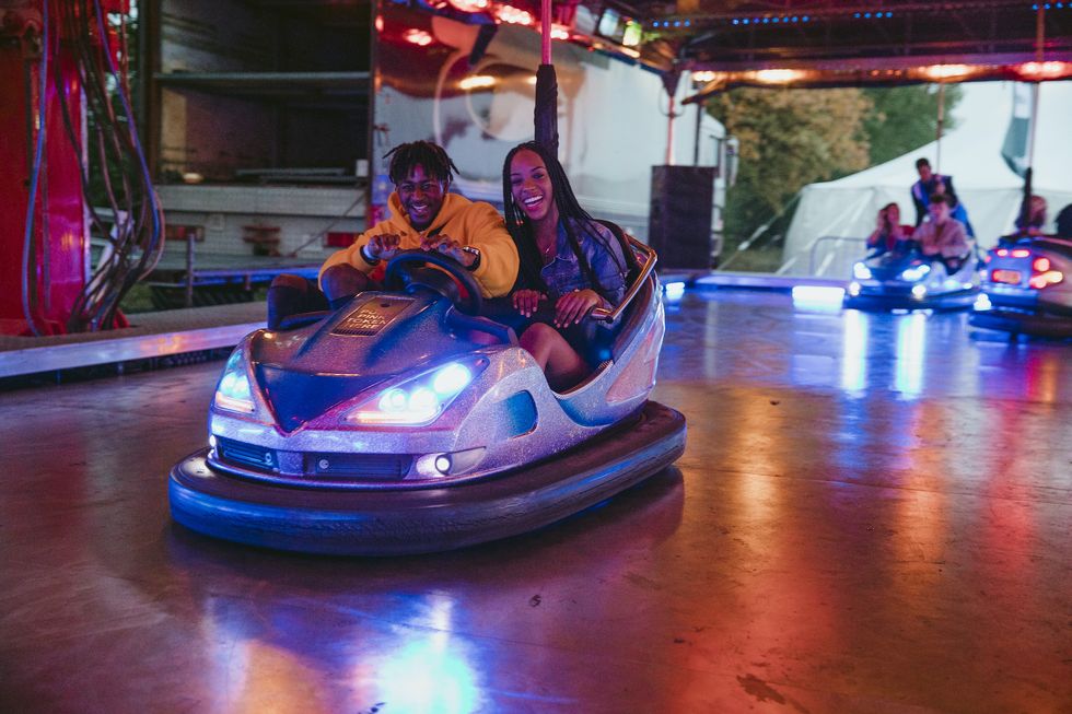 young couple are having fun racing around on bumper cars at a funfair