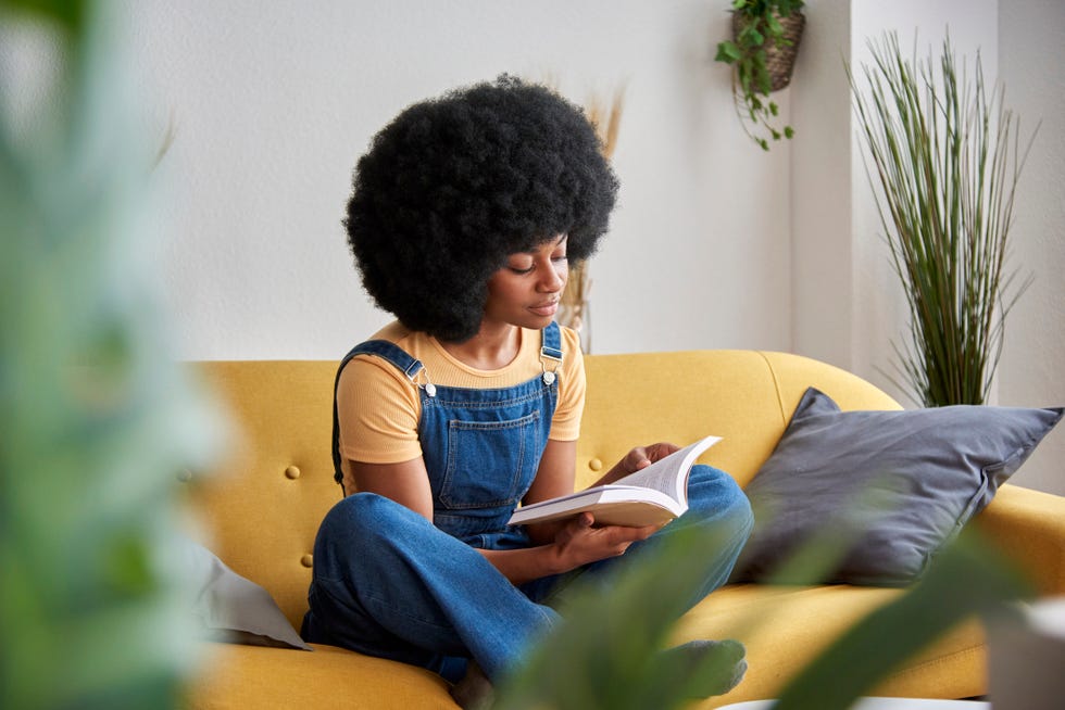 woman sitting on a yellow couch reading a book, giving up avoiding reading for lent