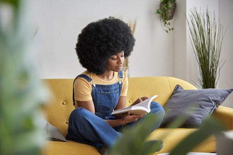 woman sitting on a yellow couch reading a book, giving up avoiding reading for lent