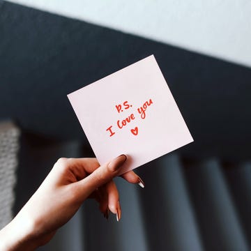 the girl holds in her hand a pink love note valentines day gray background womans hand declaration of love love note confession note