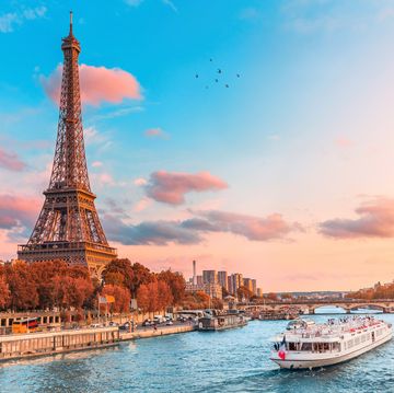 the main attraction of paris and all of europe is the eiffel tower in the rays of the setting sun on the bank of seine river with cruise tourist ships