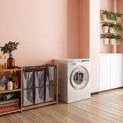 laundry room interior with washer dryer machine, laundry basket, potted plants and coral color wall