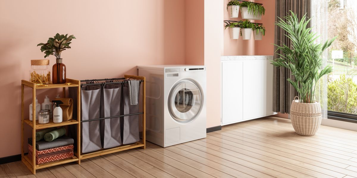 laundry room interior with washer dryer machine, laundry basket, potted plants and coral color wall