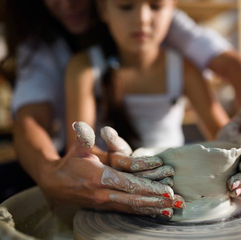 small girl being taught pottery by teacher in art studio