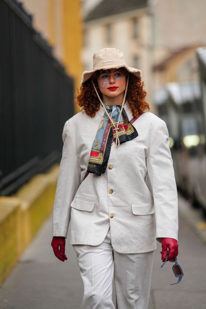 paris, france january 22 a guest wears a beige ripped bob from jacquemus, a gray gold red print pattern silk scarf, a white blazer jacket, a burgundy shiny leather crossbody bag, red shiny leather gloves, white suit pants, gray sunglasses, outside hermes, during paris fashion week menswear fw 2022 2023, on january 22, 2022 in paris, france photo by edward berthelotgetty images