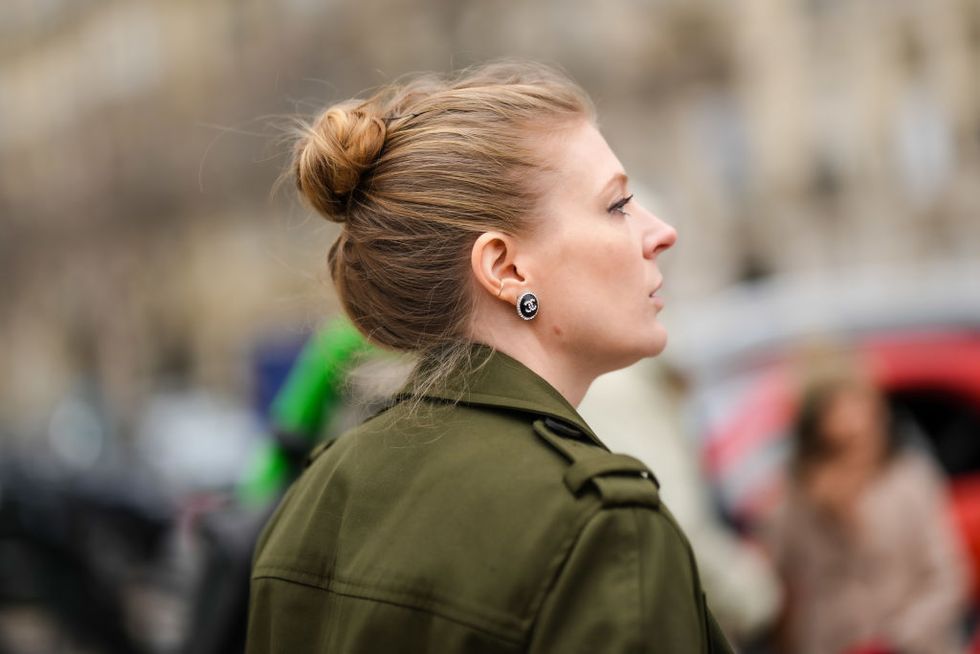paris, france january 24 a guest wears a black logo earring from chanel, a khaki long trench coat , outside chanel, during paris fashion week haute couture spring summer, on january 24, 2023 in paris, france photo by edward berthelotgetty images