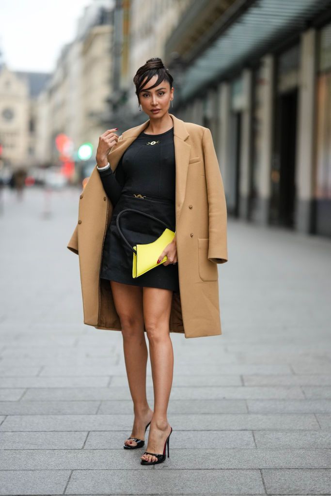 paris, france january 27 patricia gloria contreras wears a beige long jacket, a black long sleeves t shirt from patou, a black short skirt from patou, a yellow shiny leather handbag, black suede heels sandals , outside patou, at la samaritaine, on january 27, 2023 in paris, france photo by edward berthelotgetty images