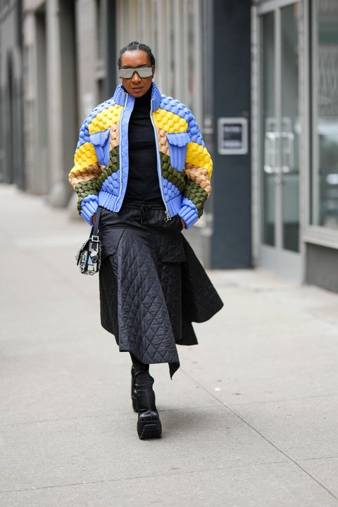 new york, new york february 12 a guest wears black futurist sunglasses from 3ny, a black wool turtleneck pullover, a pale blue yellow beige khaki print pattern embossed checkered pattern zipper high neck jacket, a black quilted midi skirt, a black shiny leather with embroidered mirror pattern handbag, black satin silk platform soles high heels knees boots , outside adeam, during new york fashion week, on february 12, 2023 in new york city photo by edward berthelotgetty images