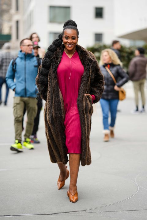 new york, new york february 12 a guest wears gold earrings, a gold long chain necklace, a dark brown fur long coat, a red pleated midi dress, a camel shiny leather with ballon heels pointed shoes from loewe , outside jason wu, during new york fashion week, on february 12, 2023 in new york city photo by edward berthelotgetty images