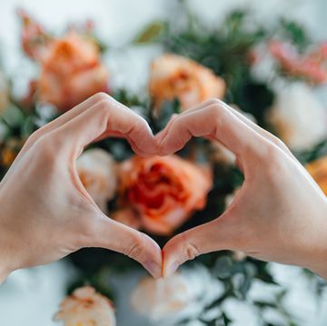 woman forming a heart with hands against flower bouquet heart made with hands receiving flower bouquet delivery on valentine’s day online dating concept long distance relationship dating anniversary