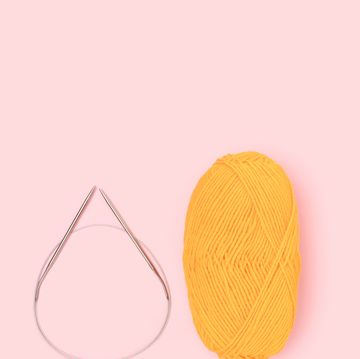 circular knitting needles and yellow yarn on pink background