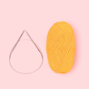 circular knitting needles and yellow yarn on pink background