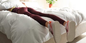 lazy young woman sleeping on bed instead of morning training, focus on legs