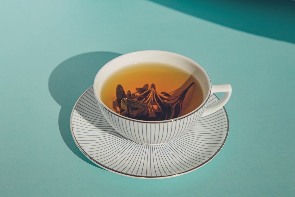 herbal green tea in a white cup with a white saucer on color background