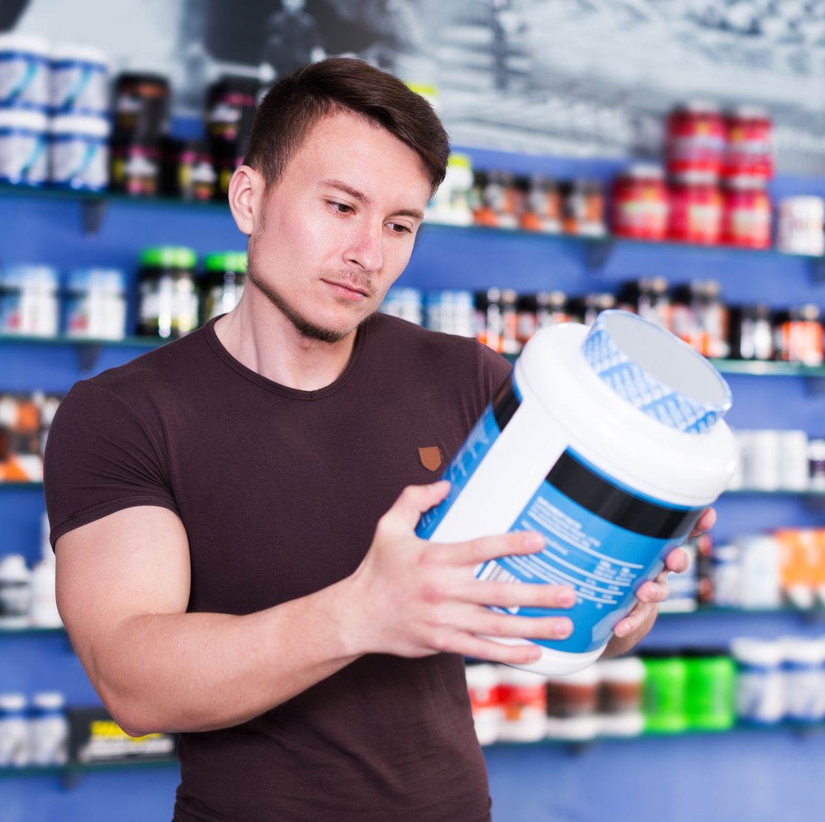 positive sporty guy looking for necessary food supplements in sport nutrition store