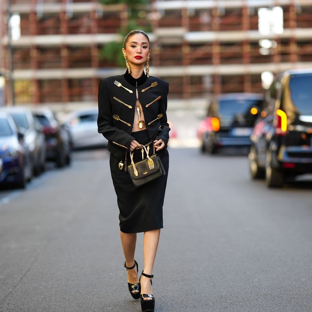 milan, italy september 22 heart evangelista wears gold large pendant earrings from moschino, a black with gold embroidered flatware jacket from moschino, a matching black with gold embroidered flatware knees pencil skirt from moschino, a black shiny leather handbag from moschino, black shiny varnished leather open toe cap high platform heels shoes , outside moschino, during the milan fashion week womenswear springsummer 2023 on september 22, 2022 in milan, italy photo by edward berthelotgetty images