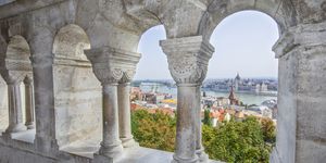 a captivating perspective captured through the arches of the fishermans bastion, revealing budapests enchanting panorama the citys beauty framed by history, where old world charm meets modern splendor