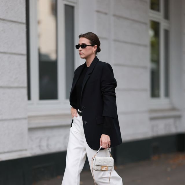 hamburg, germany september 20 marie danker is seen wearing black narrow sunglasses from carolina lemke, golden hoop earrings from missoma, a black long blazer with shoulder pads from leger, underneath a black cashmere pullover, wide white jeans pants from cos, a black leather belt with golden buckle from cos, the baguette bag from fendi in white leather and black leather boots with squared toecaps from zara on september 20, 2023 in hamburg, germany photo by jeremy moellergetty images