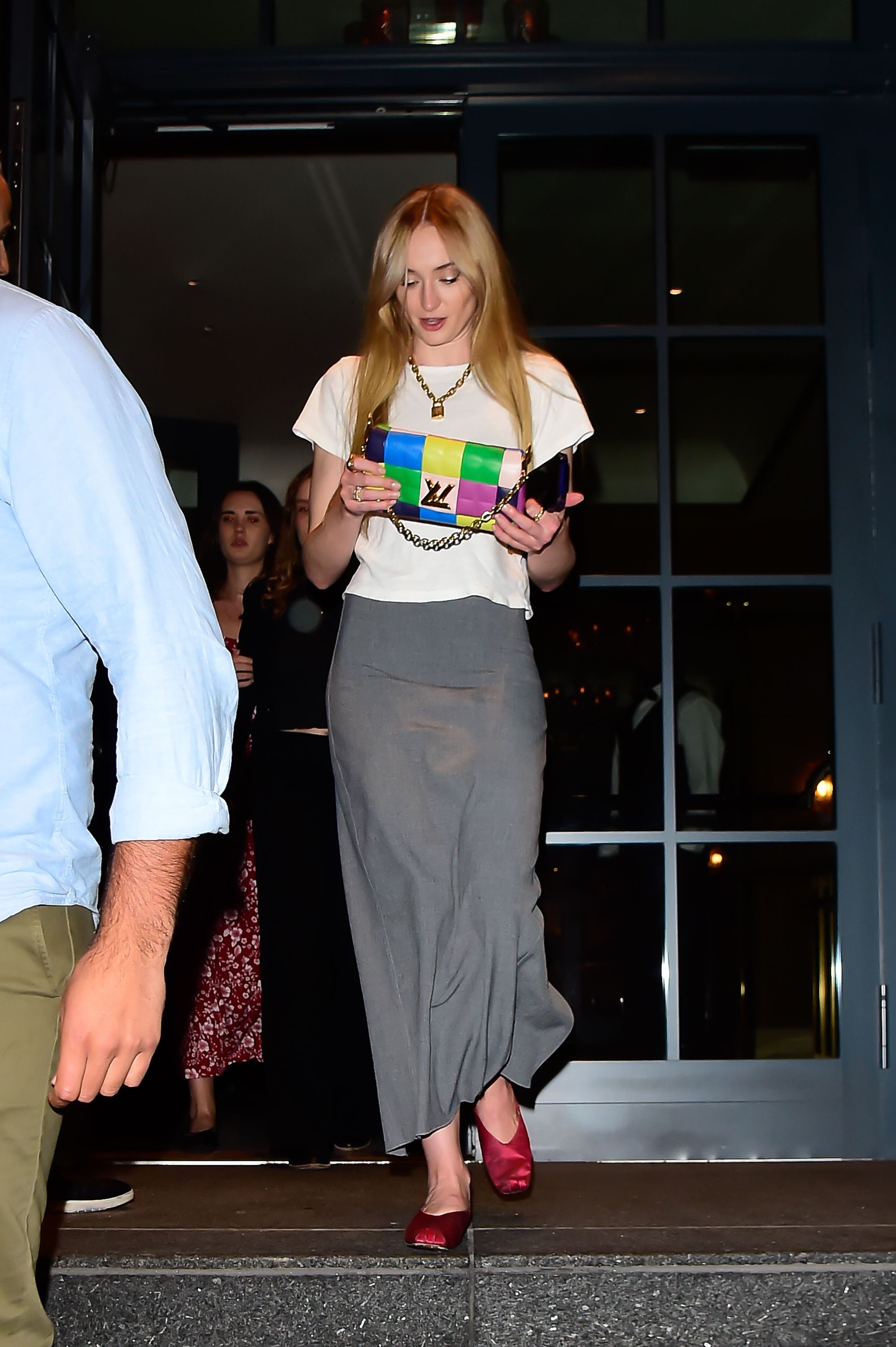 A guest wears gold chain necklaces, a black shirt, a black embossed News  Photo - Getty Images